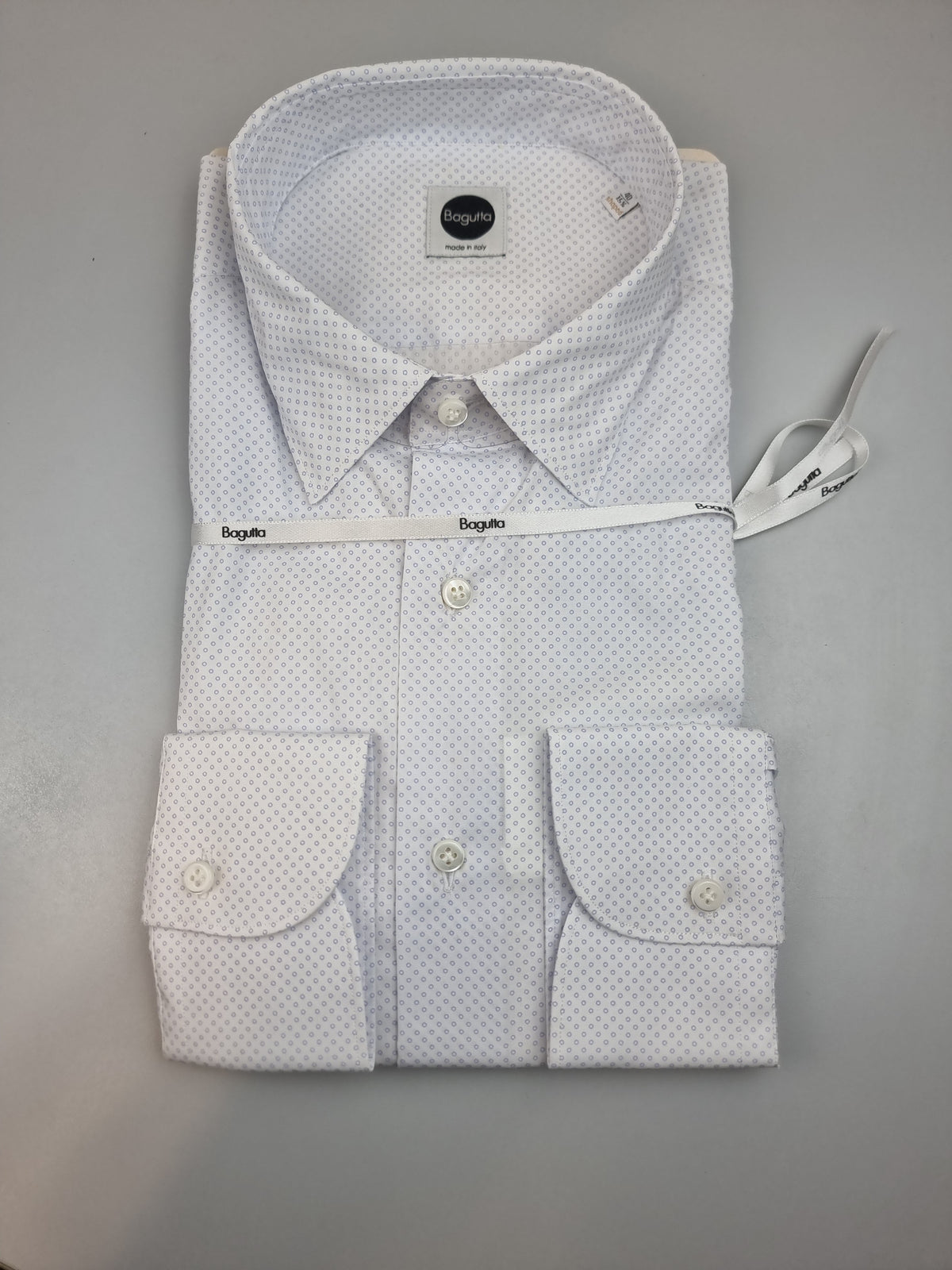 Camicia da uomo Bagutta BC342L arricchisce la base bianca con una microfantasia di cerchietti celesti, un dettaglio discreto per chi desidera un'alternativa alla tinta unita. Vista piegata.