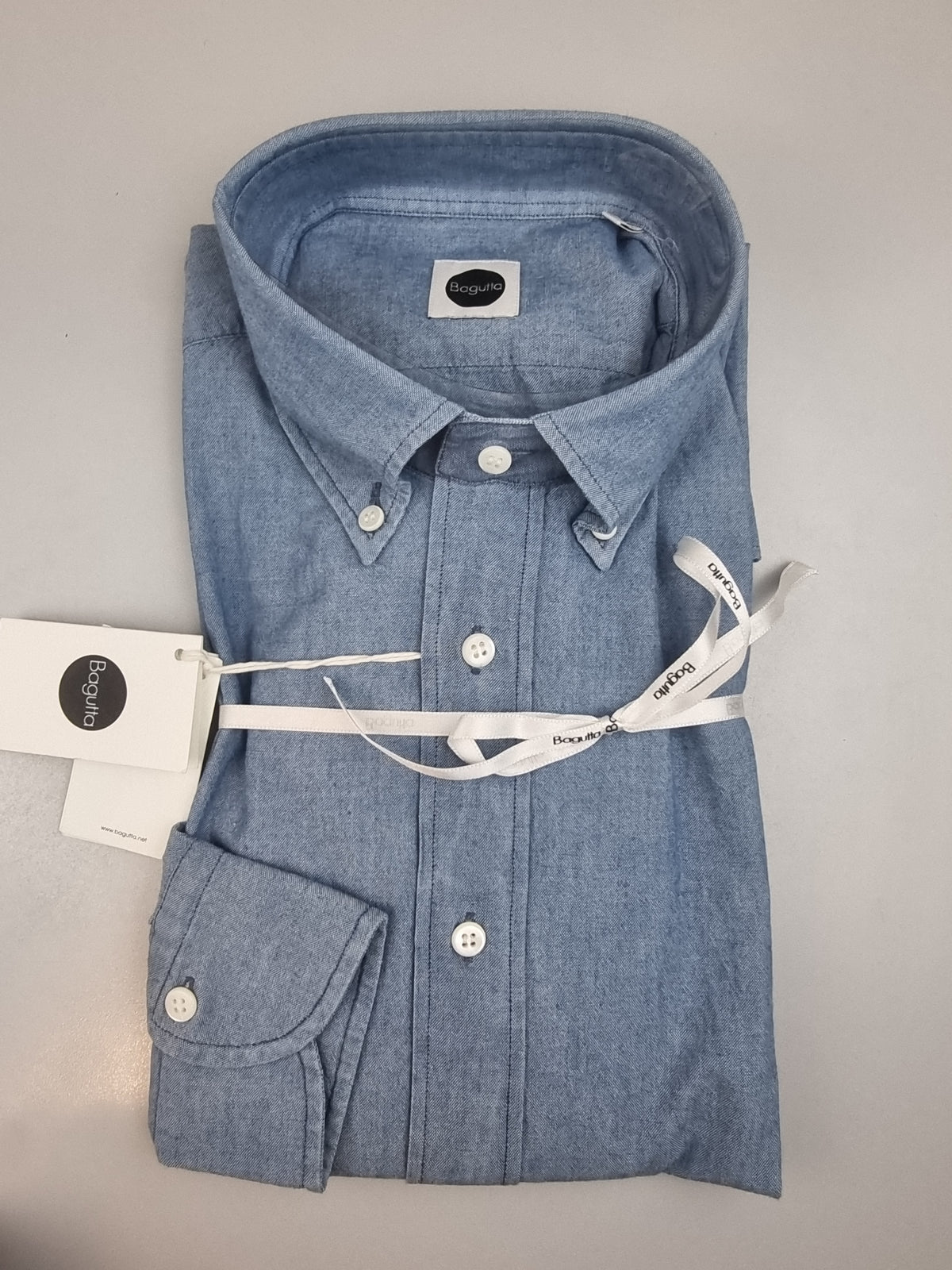 La camicia da uomo Bagutta A0140J abbina il denim chiaro alle cuciture scure a contrasto, per un look casual dal carattere definito. Realizzata in 100% cotone con vestibilità regular, presenta collo francese e abbottonatura con cannoncino, dettagli che permettono di interpretarla anche con abbinamenti più curati. Vista piegata.