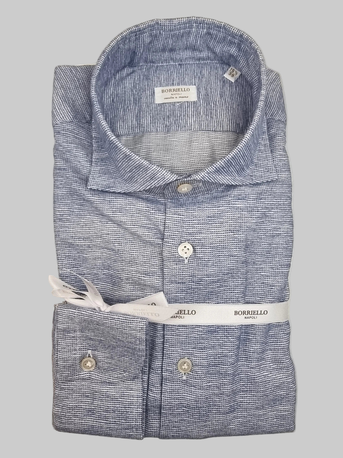 La camicia da uomo Borriello 9303-2 interpreta la base bianca con una microfantasia pied de poule blu, un'alternativa alla tinta unita per chi ama i dettagli discreti. Vista piegata.