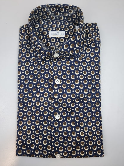 La camicia da uomo Sonrisa B878 combina il blu con dettagli di fantasia nei toni del marrone e del beige. Realizzata in 100% cotone, indicato come fior di cotone, presenta vestibilità classica, collo francese e polsini con bottoni: una proposta per dare personalità a un look curato. Vista piegata.