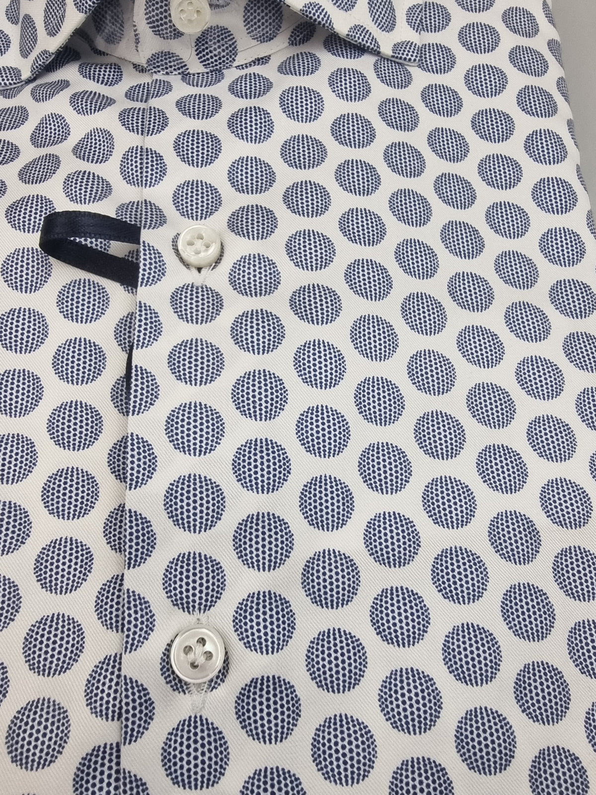 Camicia Sonrisa bianca con pois geometrici blu.
La camicia da uomo Sonrisa Superior arricchisce la base bianca con una fantasia di pois geometrici blu, per chi cerca un dettaglio distintivo negli abbinamenti quotidiani. Vista particolare colore e fantasia.